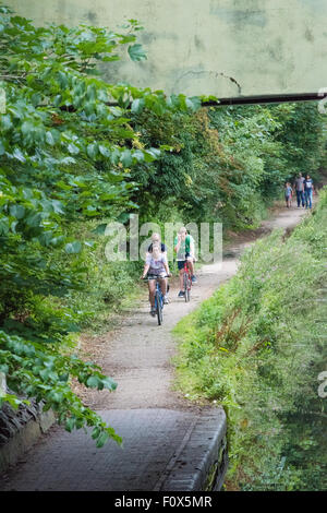 Eine Familie, Fahrradfahren entlang der Leinpfad des Kanals mit einer anderen Familie zu Fuß hinter in der Ferne Wolverhampton UK Stockfoto