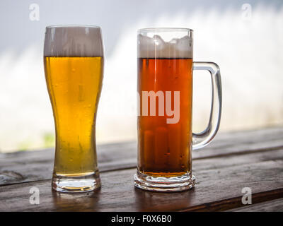 Bierkrug und Glas mit hellen oder dunklen Getränke Stockfoto