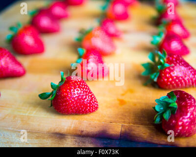 Reihen von Erdbeeren auf einem Holzbrett Stockfoto