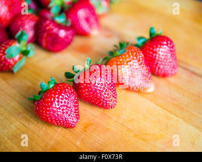 Reihe von Erdbeeren auf einem Holzbrett Stockfoto