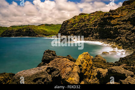 Eine Langzeitbelichtung Foto von der zerklüfteten Küste in der Nähe der Nakalele Blasloch West Maui Hawaii USA mit weißen flauschigen Wolken. Stockfoto