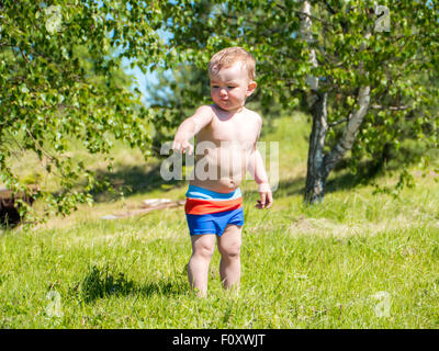 Kleinen Jungen zu Fuß auf einer grünen Wiese Stockfoto