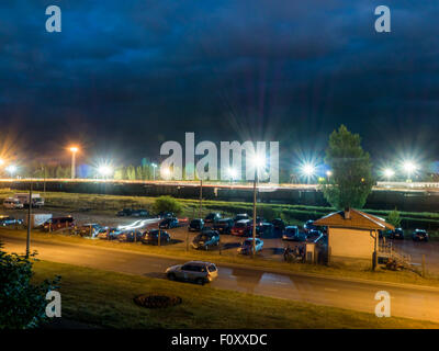Parkplatz in der Nacht mit Straßenlaternen und erstaunlich dunkle Wolken Stockfoto