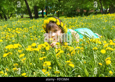 Europäischen Dame Brünette in Kranz von gelben Löwenzahn Wiese mit Löwenzahn auflegen. Stockfoto