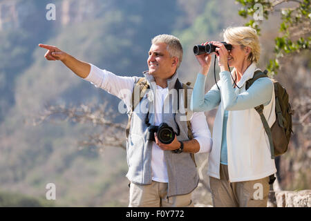 schöne weibliche Wanderer mit dem Fernglas während Mann zeigen Stockfoto