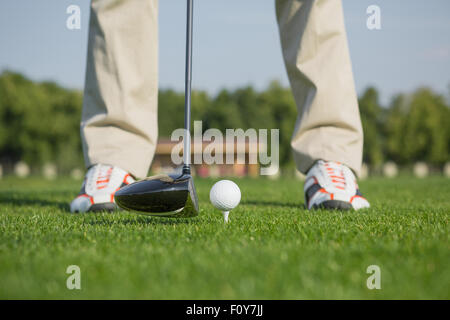 Golfball auf der grünen Wiese. Mann geht um einen Ball von einem Fahrer. Männlichen Golfer schießen einen Golfball vom Abschlag auf grünen Kurs. Stockfoto