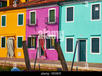 Bunte Reihe von Canalside Häuser und hölzernen Liegeplatz Stangen Burano venezianischen Lagune Veneto Italien Europa Stockfoto