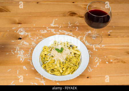 Tagliatelle Nudeln mit Pesto und Basilikum Blätter auf weißen Teller, Holz Hintergrund Stockfoto