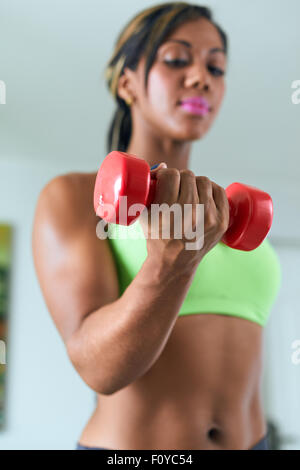 Junge afrikanische amerikanische Frau im Sport Kleidung zu Hause, häusliche Fitness zu tun und training Bizeps mit Gewicht. Im Fokus Stockfoto