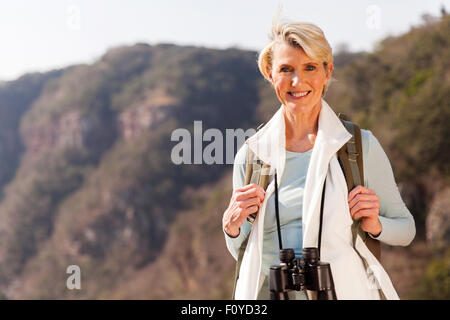 schöne mittlere gealterte Frau oben auf dem Berg mit dem Fernglas Stockfoto