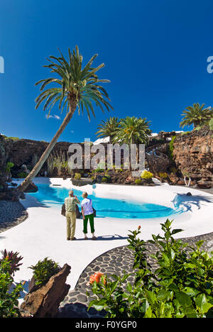 LANZAROTE Jameos del Agua touristische Paar unter Foto von klaren türkisblauen Pool mit Palmen und tropischen Pflanzen, Manrique, Lanzarote Kanarische Inseln Spanien Stockfoto