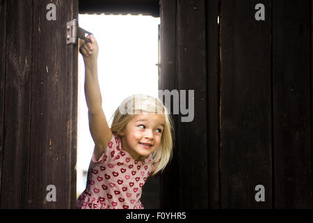 Blonde Mädchen Kind hinter Holztor, auf der Suche Stockfoto