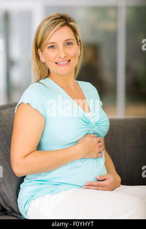 Porträt von glücklich schwangere entspannend auf sofa Stockfoto