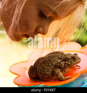 Kind blondes Mädchen Blick auf Hinterhof Frosch Stockfoto