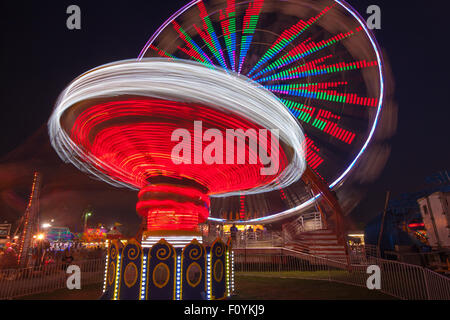 Bunt beleuchtete Fahrgeschäfte drehen gegen den Nachthimmel während der New Jersey State Fair in Augusta im US-Bundesstaat New Jersey. Stockfoto