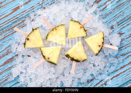 Ananas Eis am Stiel leckeren frischen sommerlichen Obst süßes Dessert auf Vintage alte Holz Teak blau Stockfoto