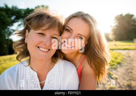 Porträt der Mutter und ihre Tochter im Teenageralter im Freien in der Natur mit Sonnenuntergang im Hintergrund Stockfoto