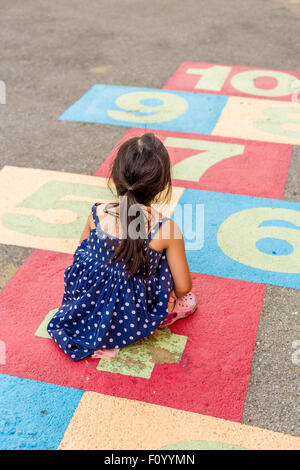 Junges Mädchen Spiel Himmel und Hölle auf Spielplatz mit Glück. Stockfoto