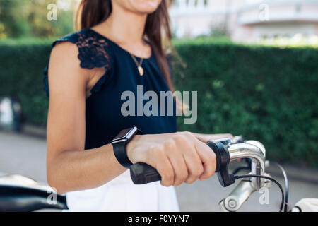 Frau mit dem Fahrrad mit einer Smartwatch. Weibchen tragen Smartwatch beim Radfahren. Stockfoto
