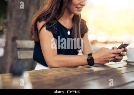 Frau Textmitteilung auf smart Phone in einem Café zu schreiben. Bild junge Frau sitzt an einem Tisch mit einem Kaffee mit mobilen p beschnitten Stockfoto