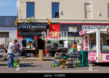 Stall-Inhaber an der berühmten Glasgow Street Market, The Barras, Verkauf von secondhand Spielzeug und Galanteriewaren mit einem van Essen in der Nähe. Stockfoto