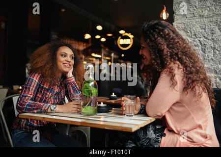 Aufnahme von zwei jungen Frauen sitzen in einem Restaurant im Gespräch. Glückliche junge Freundinnen treffen in einem Café. Stockfoto