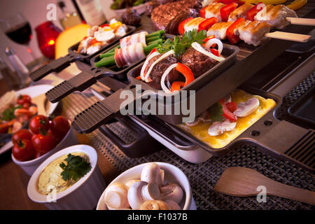 Schweizer Raclette oder die niederländische Variante "Gourmetten". Eine Tabelle mit Zutaten für ein Gericht, die in der Regel auf Celebrato serviert wird gefüllt Stockfoto