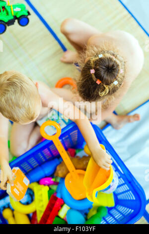 Schöne kleine Kinder spielen mit Plastikspielzeug im freien Stockfoto