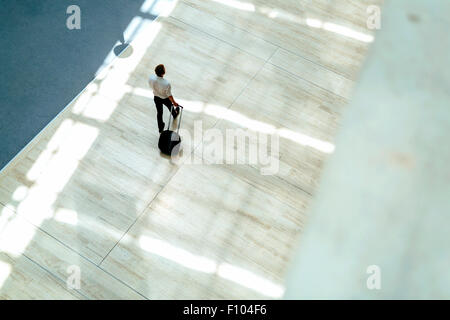 Gut aussehend Geschäft hält einen Wagen und zu Fuß in einem modernen Gebäude, die von oben gesehen Stockfoto