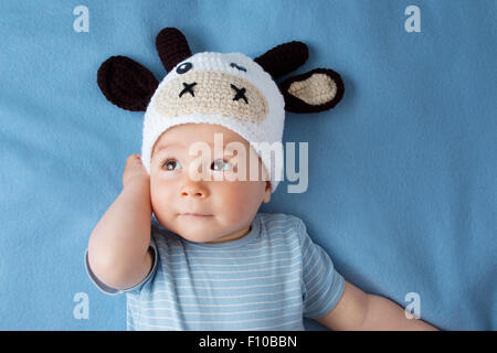 Baby in einem Kuh-Hut auf blaue Decke Stockfoto