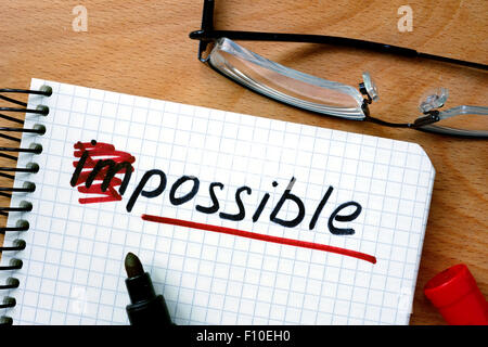 Notizblock mit der Umwandlung des Wortes unmöglich möglich am Bürotisch aus Holz. Stockfoto