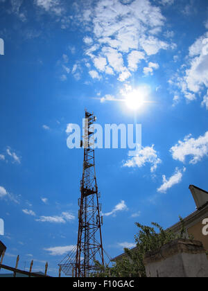 Turm des Mobilfunkes gegen den blauen Himmel und strahlende Sonne mit fisheye-Objektiv und Verzeichnung Weitwinkel Stockfoto