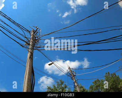 Polen mit einer Menge von Drähten und elektrische Lampen Beleuchtung vor blauem Himmel mit Weitwinkel Verzerrung Stockfoto