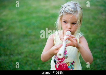 Kind blondes Mädchen spielen Querflöte Blockflöte, outdoor Portrait im Hinterhof Stockfoto