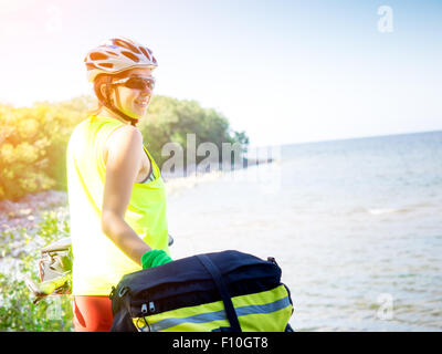 Junge Frau mit dem Fahrrad stehen direkt am Meer Stockfoto