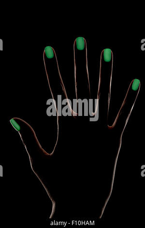 Weibliche Hand Silhouette auf schwarzen Hintergrund mit Konturbeleuchtung und grün leuchtende Nageldesign Stockfoto