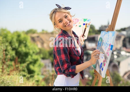 Schöne blonde Frau Künstler malt ein buntes Bild. Stockfoto