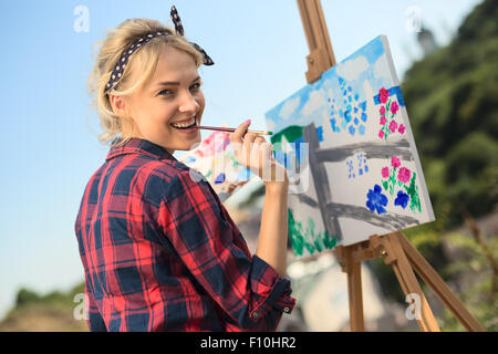 Schöne blonde Frau Künstler malt ein buntes Bild. Stockfoto