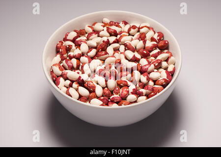 Rohe organische Bohnen in weißer Keramik Schüssel auf weißem Hintergrund Stockfoto