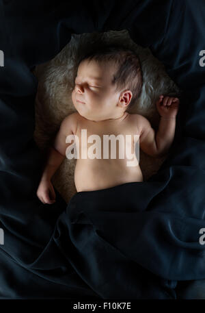 Niedliche neugeborenes Baby schlafen auf weiße Wolldecke, bedeckt mit schwarzem Stoff Stockfoto