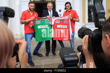 Magdeburg, Deutschland. 24. August 2015. Ministerpräsident von Sachsen-Anhalt, Reiner Haseloff (CDU, in der Mitte), dänische Handball Torwart Jannick grün Krejberg (rechts) und der niederländischen Defensivspieler Fabian van Olphen (links) vom SC Magdeburg präsentieren die neuen Trikots mit dem Logo "Willkommen Weltoffen Sachsen-Anhalt" (lit.) "Begrüßen Sie aufgeschlossen Sachsen-Anhalt) während einer Pressekonferenz in Magdeburg, Deutschland, 24. August 2015." Die neuen Trikots werden für die kommende Europameisterschaft verwendet. SC Magdeburg-Team besteht aus Spielern aus acht verschiedenen Nationen. Foto: JENS WOLF/Dpa/Alamy Live News Stockfoto