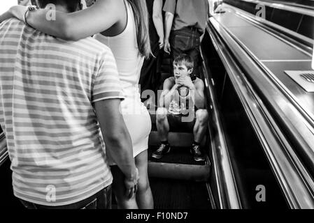 Kiew, Ukraine. 24. August 2015. Einsame junge sitzt auf der Rolltreppe, Reiten bis zur Station Platz der Unabhängigkeit. Auf der Vorder- und Hintergrund sind zwei umfassende Paare. --Tausende Ukrainer feiern den 24 Jahrestag der Unabhängigkeit der Ukraine Masse Festlichkeiten in Städten und Dörfern quer durch das Land. Dieser Urlaub getrübt durch russische Aggression im Osten der Ukraine und der Besetzung der Krim. Ukrainer sind in der Hoffnung, dass 25 Unabhängigkeitstag, sie treffen sich in einer ruhigen Umgebung. © Igor Golovnov/Alamy Live-Nachrichten Stockfoto