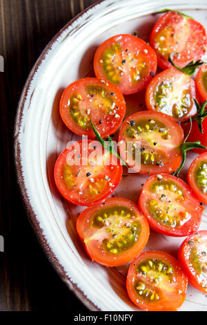 Bio Chery Tomaten mit schwarzem Pfeffer und Meersalz auf Teller, vegetarische Vorspeise Stockfoto