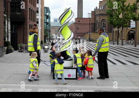 Kinder im Kindergartenalter mit Kinderbetretern in gut sichtbaren Leuchtstoffjacken auf dem Walk in City of London, Großbritannien, KATHY DEWITT Stockfoto