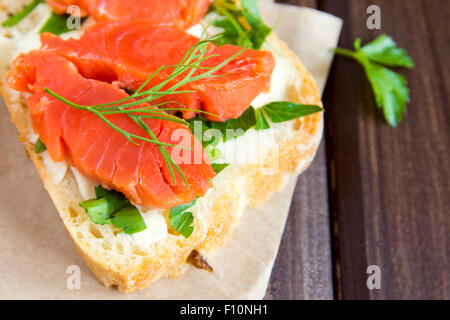 Sandwich mit Rauch Lachs (Forelle), Frischkäse, Tomaten und Petersilie auf rustikalen hölzernen Hintergrund hautnah Stockfoto