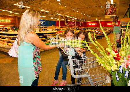 Mutter mit ihrem 2girls (Alter 6 und 9) sind in einem Supermarkt einkaufen und Produktetiketten für Ernährung Wert lesen lernen Stockfoto