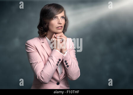 Ernste junge Frau mit ihrer Hände im Gebet und Flehen mit einem betroffenen ernsten Ausdruck der Vorbereitung nachschlagen Stockfoto