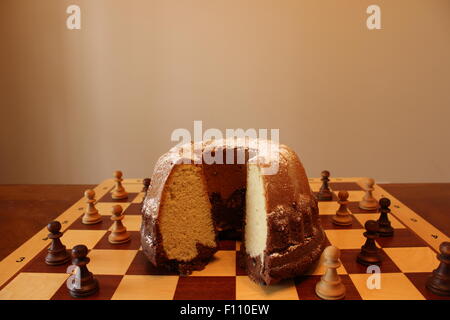 Kuchen auf umgeben von Schachfiguren Schachbrett Stockfoto