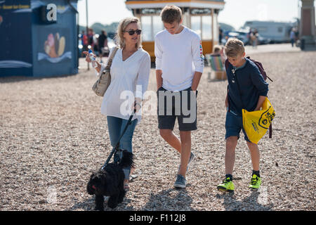 Eine Mutter und ihre zwei Söhne im Teenageralter spazieren ein Kiesstrand in Portsmouth mit ihrem schwarzen Cockapoo Hund Stockfoto