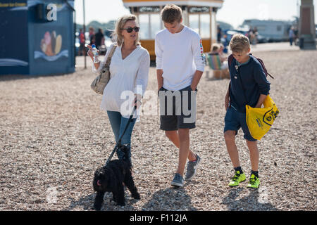 Eine Mutter und ihre zwei Söhne im Teenageralter spazieren ein Kiesstrand in Portsmouth mit ihrem schwarzen Cockapoo Hund Stockfoto